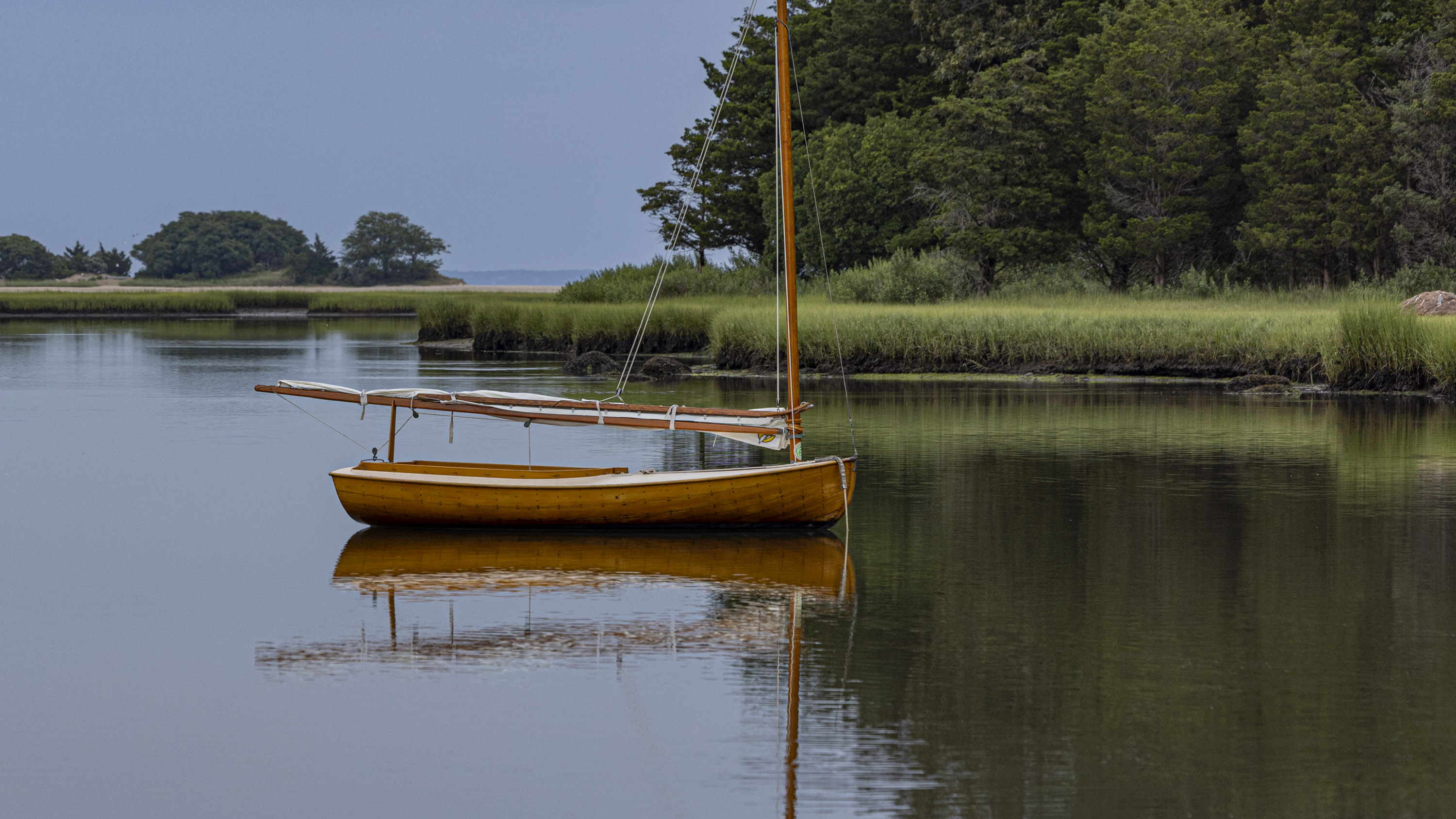 sailboat on a calm inland waterway, sail stowed, a kingfisher bird on its mast